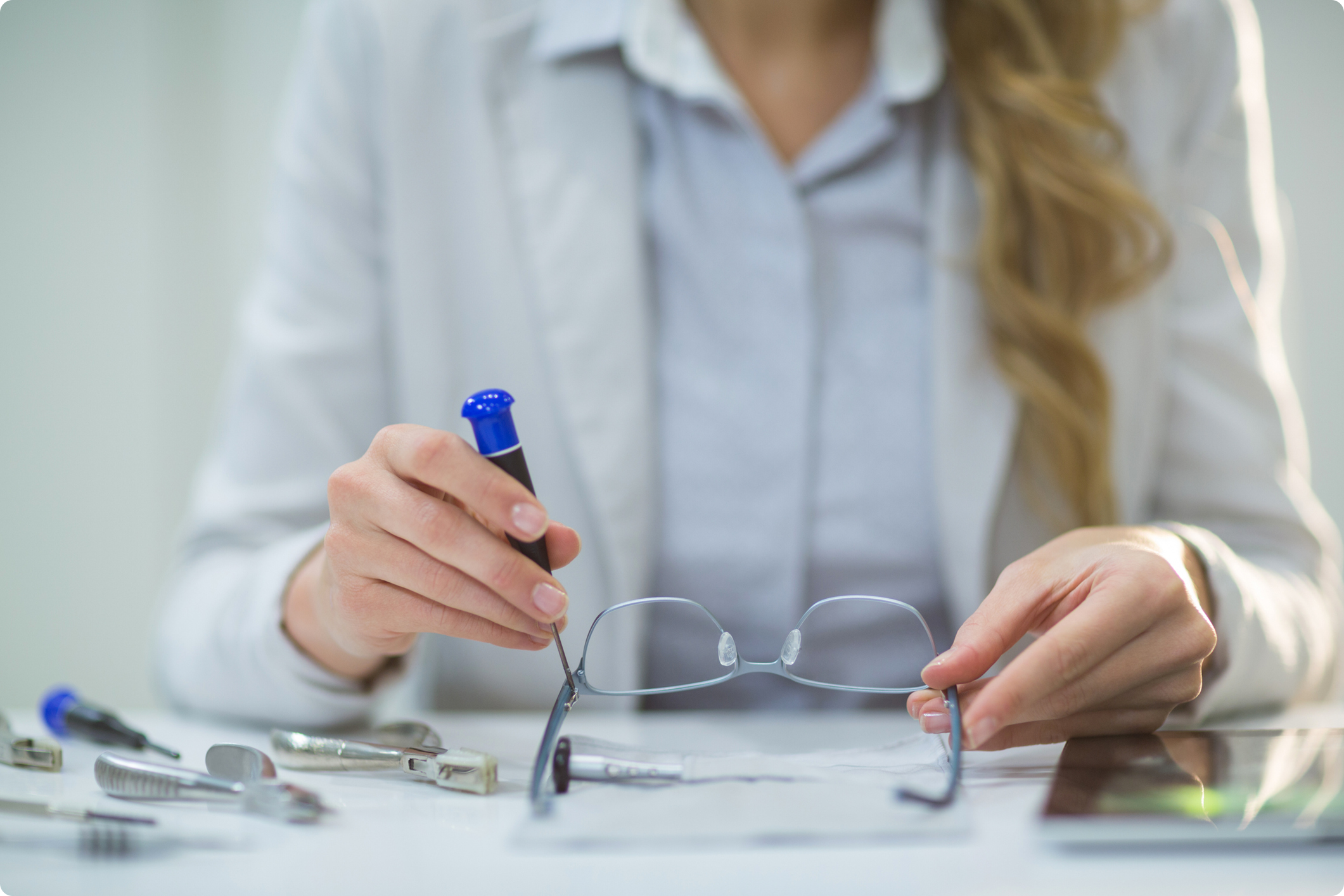 Optician repairing eyeglasses with tools.
